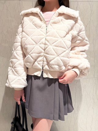 Model wearing the ivory SNIDEL Faux Fur Blouson with diamond quilting, styled with a gray pleated mini skirt.