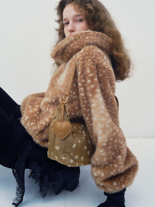 Seated model wearing the brown spotted SNIDEL Faux Fur Blouson with its large collar raised.