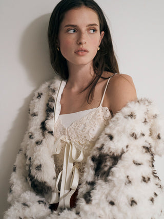 Close-up of the white and brown patterned SNIDEL Faux Fur Blouson worn off one shoulder.