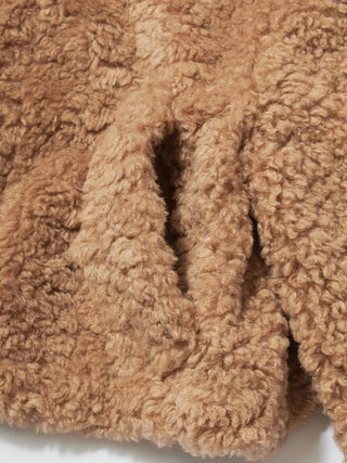 Close-up of a warm camel brown sherpa fleece texture with soft, curly loops and a folded edge showing the plush depth.