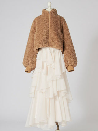 A cropped teddy fleece jacket in camel brown with a high collar and long sleeves, styled on a mannequin with a cream ruffled tiered skirt against a light gray studio background.