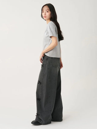 A woman modeling a light gray short-sleeve t-shirt and dark gray wide-leg distressed jeans against a plain light gray studio background.