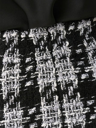 Close-up of a black and white tweed fabric texture with a dark solid section above it.