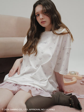 Seated model wearing the pink SNIDEL Twist Frill Mini Skort with an oversized white printed T-shirt.