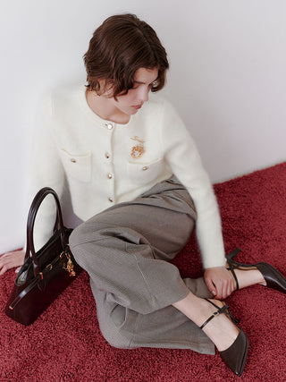 Seated model wearing the checked SNIDEL Belted Tuck Pants with an ivory cardigan and dark slingback heels.