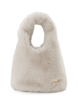 A fluffy faux-fur handbag in a light cream or oatmeal color, featuring a distinctive top handle cutout and a small gold brand tag near the bottom right.