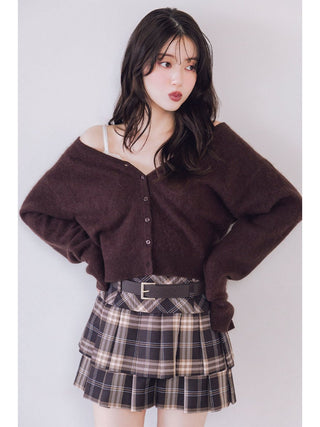 A young woman modeling a dark brown fuzzy off-the-shoulder button-up cardigan and a brown, black, and beige plaid pleated mini skirt with a black belt.