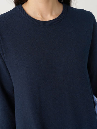 A close-up of a person wearing a dark navy blue crewneck knit sweater, showing the ribbed collar and fine knit texture.