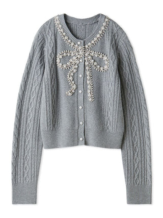A light gray cable-knit cardigan sweater featuring a decorative bow embellishment on the chest with silver rhinestone-like details and white buttons, shown against a plain white background.