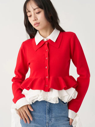 A woman wearing a bright red long-sleeve knit cardigan with a white collar and a white ruffled hem, styled with blue jeans against a light gray studio background.