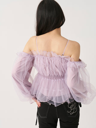 A woman shown from the back wearing a light lavender off-the-shoulder tulle top with long sheer puff sleeves and black pants, against a plain light background.