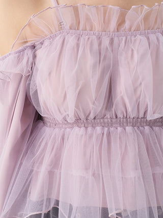 Close-up of a light pink tulle dress with ruffled straps, a gathered waist, and layered sheer fabric.